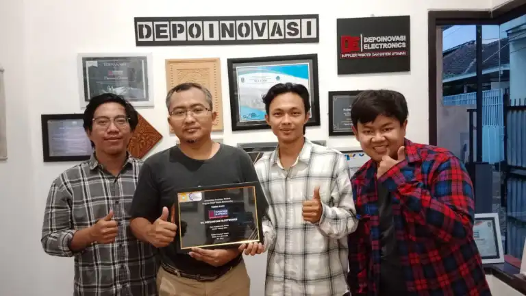 Tim mahasiswa berfoto bersama pembimbing sambil memegang plakat penghargaan